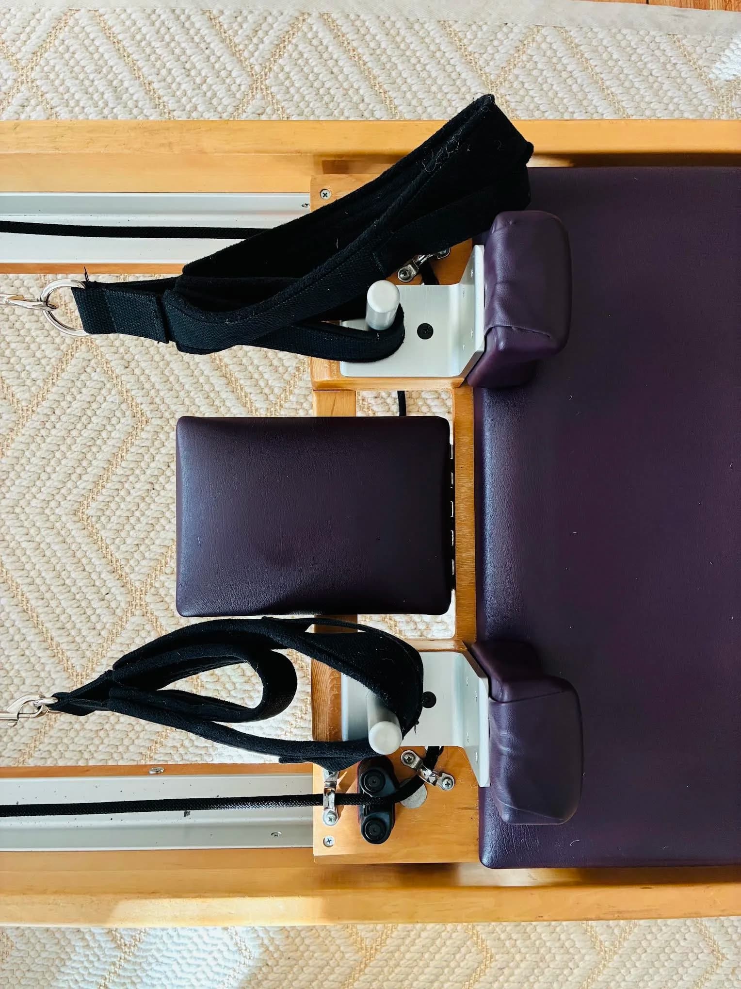 Top-down detail of a reformer with purple leather upholstery and straps