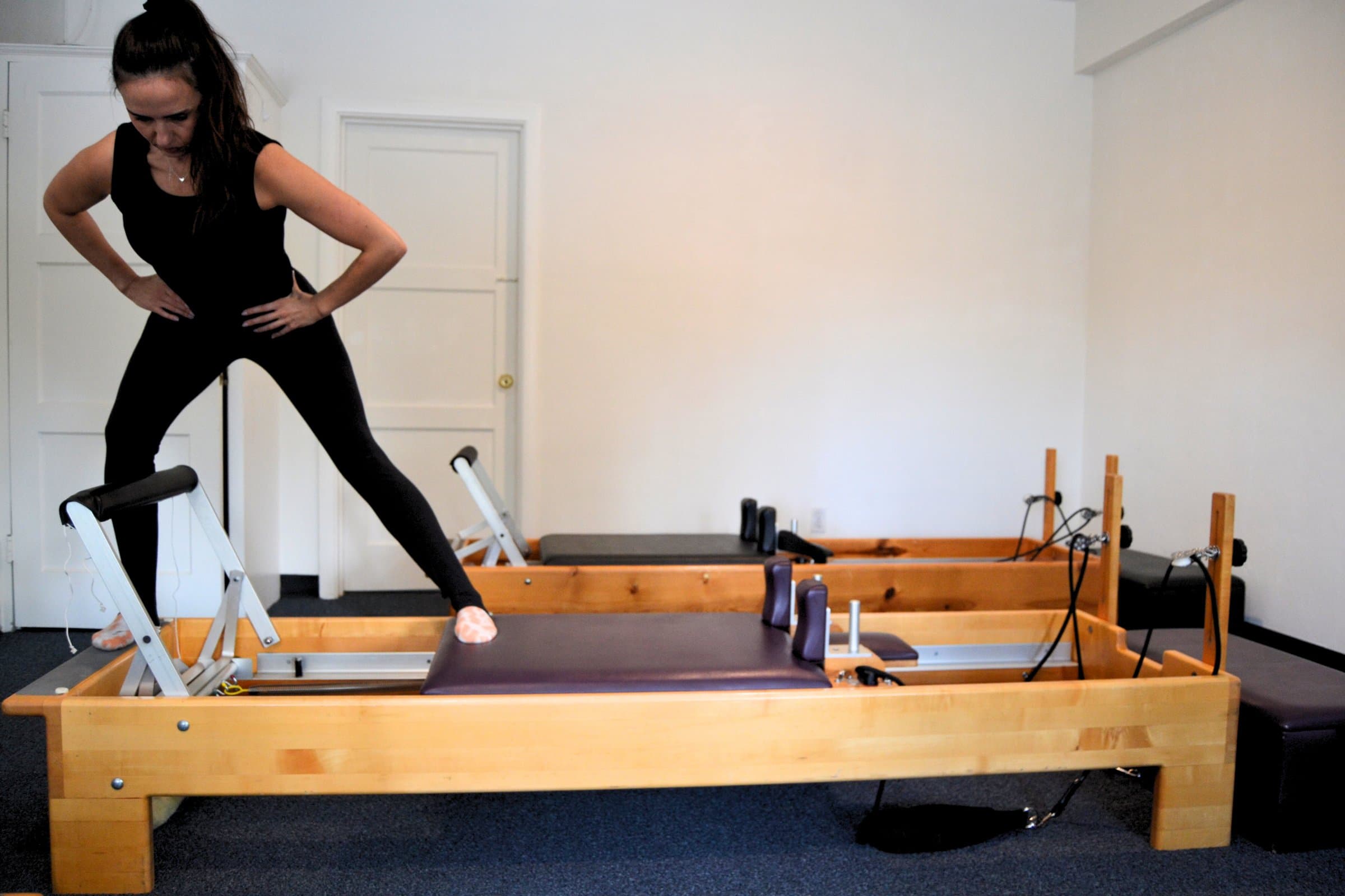 A client standing on a reformer during a training session at Embodied Pilates